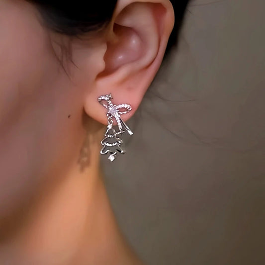 Model showcasing the dangle and style of the 18K Gold-Plated Christmas Tree And Bell Asymmetrical Earrings