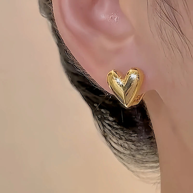 Solid gold starburst engraved heart stud earring on ear