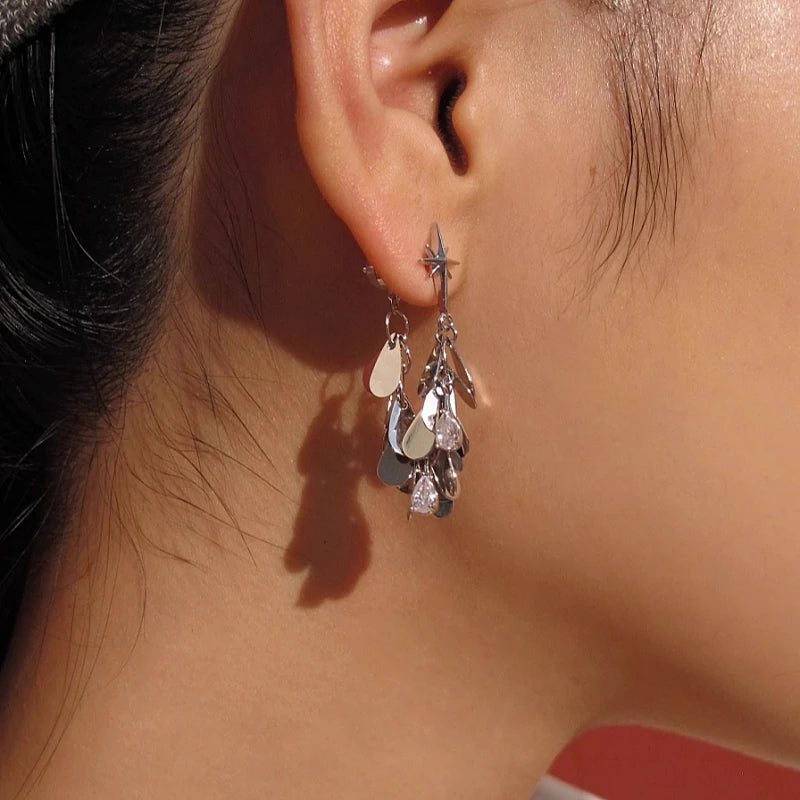Silver starburst teardrop crystal dangle earring worn on ear