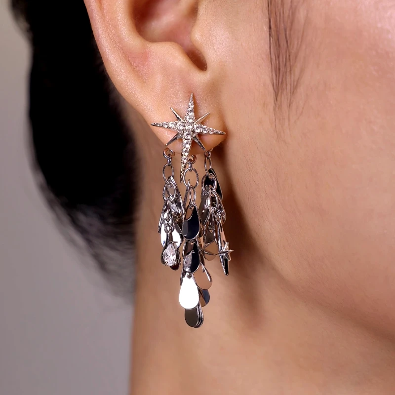 Silver starburst dangling disc drop earring with crystal accents, worn on ear