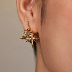 Gold CZ star and planet stud earring on model's ear