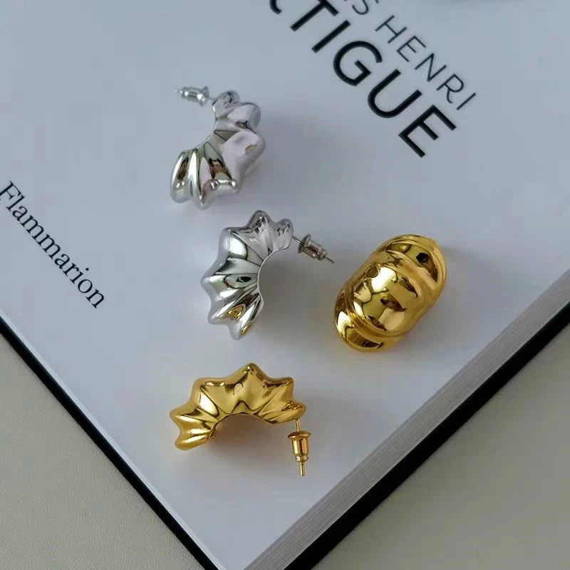 Gold and silver sculptural ribbed statement hoop earrings on book page