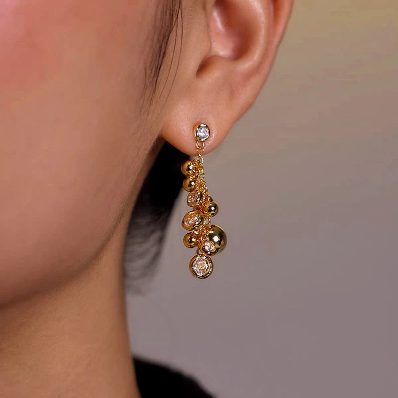 Gold bubble crystal dangle drop earring worn on female earlobe