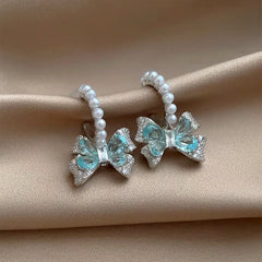 Model showcasing the dangle and style of the 18K Gold-Plated Zircon Bow Pearl Earrings