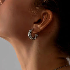 Silver quilted C-shaped hoop earring worn on a woman's ear