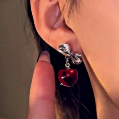 Angled view of the Silver Post Christmas Bow Cherry Earrings