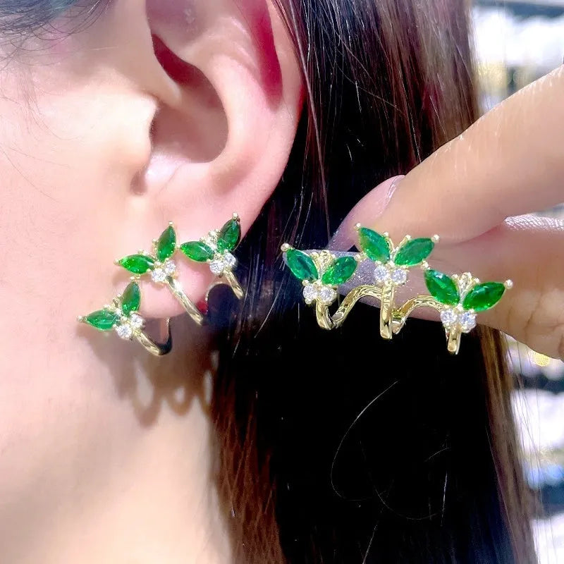 Left ear gold green butterfly ear climber, matching pair held for display