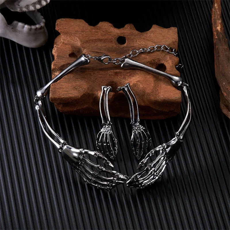 Skeleton hand choker and pair of earrings set displayed with gothic skull decor