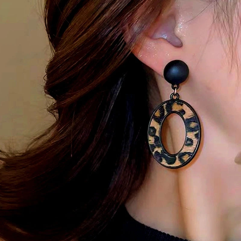Model showcasing the dangle and style of the Silver Post Oval Leopard Print Earrings