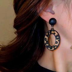 Model showcasing the dangle and style of the Silver Post Oval Leopard Print Earrings