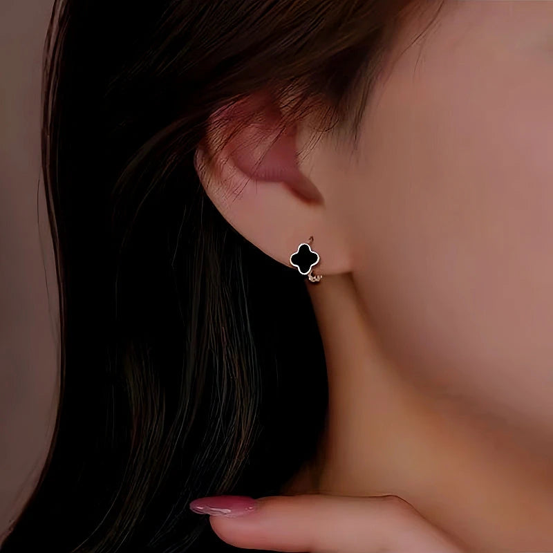 Model showcasing the dangle and style of the Sterling Silver Black Four-Leaf Clover Hoop Earrings