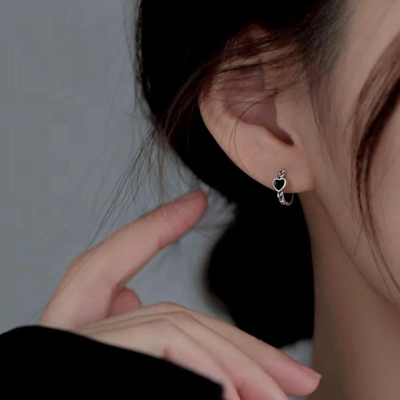 Model showcasing the dangle and style of the Sterling Silver Black Heart Hoop Earrings