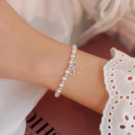 Model wearing the Sterling Silver Bow Pearl Bracelet to highlight its design on the wrist
