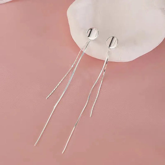 Model showcasing the dangle and style of the Sterling Silver Brushed Round Snake Bone Chain Tassel Earrings