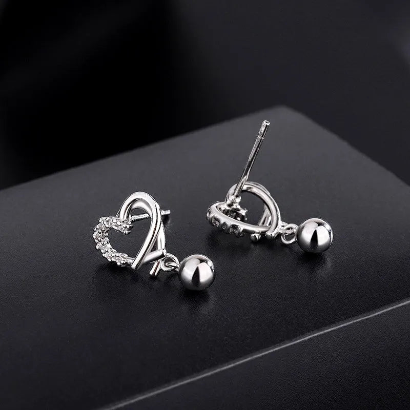 Angled view of the Sterling Silver Diamond Hollow Heart Bean Earrings