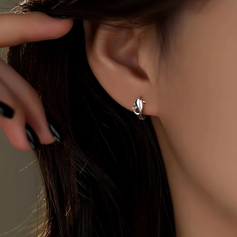Model showcasing the dangle and style of the Sterling Silver Dolphin Hoop Earrings