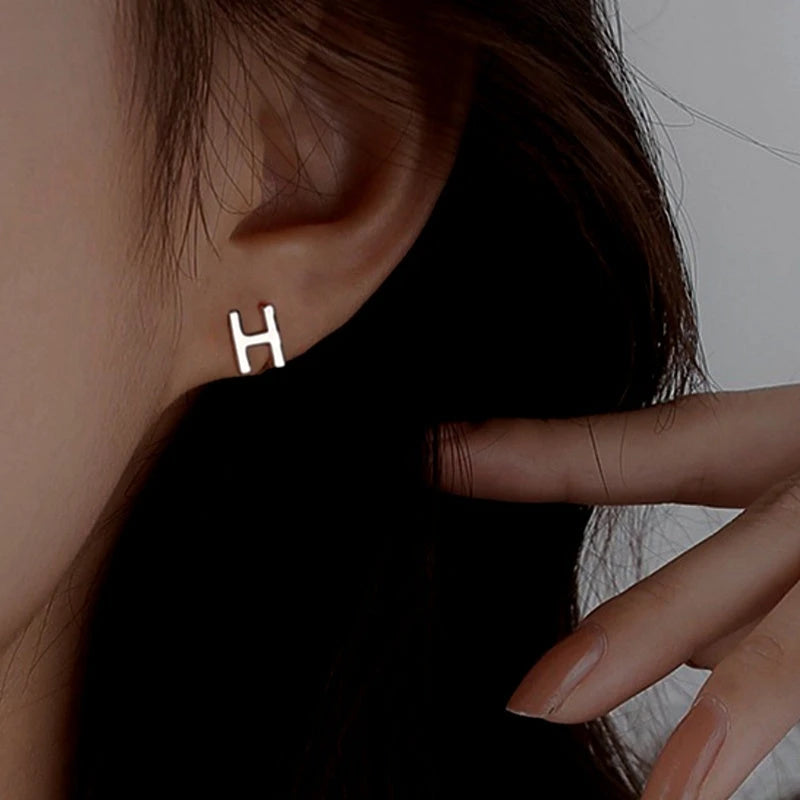 Model showcasing the dangle and style of the Sterling Silver Double-Sided Letter H Stud Earrings