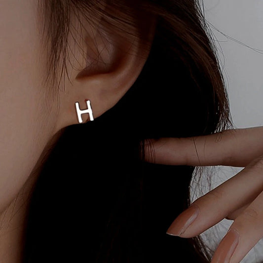 Model showcasing the dangle and style of the Sterling Silver Double-Sided Letter H Stud Earrings