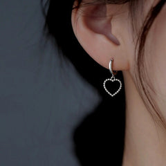 Model showcasing the dangle and style of the Sterling Silver Elegant Simple Hollow Heart Earrings