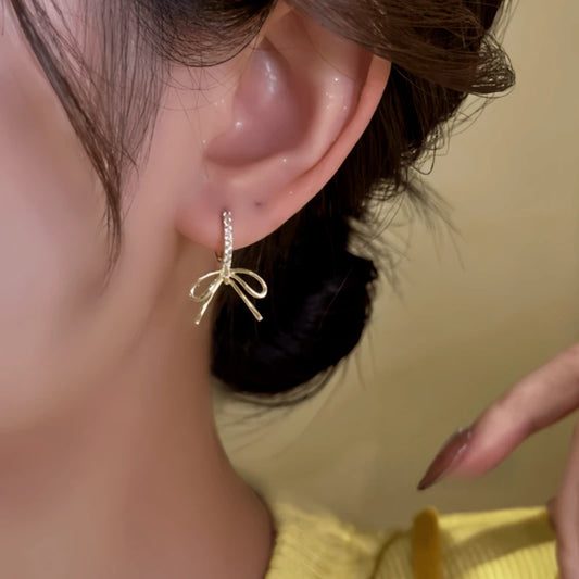 Model showcasing the dangle and style of the 14K Gold-Plated Elegant Zircon Bow Earrings