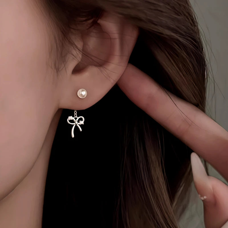 Model showcasing the dangle and style of the Sterling Silver Elegant Zircon Diamond Bow Pearl Earrings