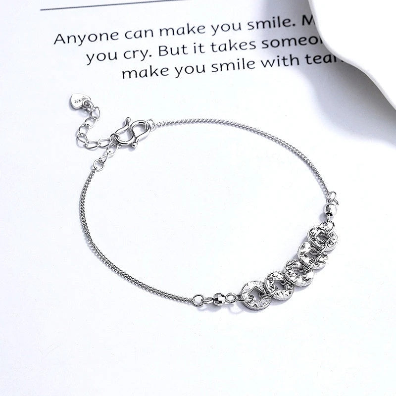 Close-up of the clasp and charm details on the Coin Bracelet