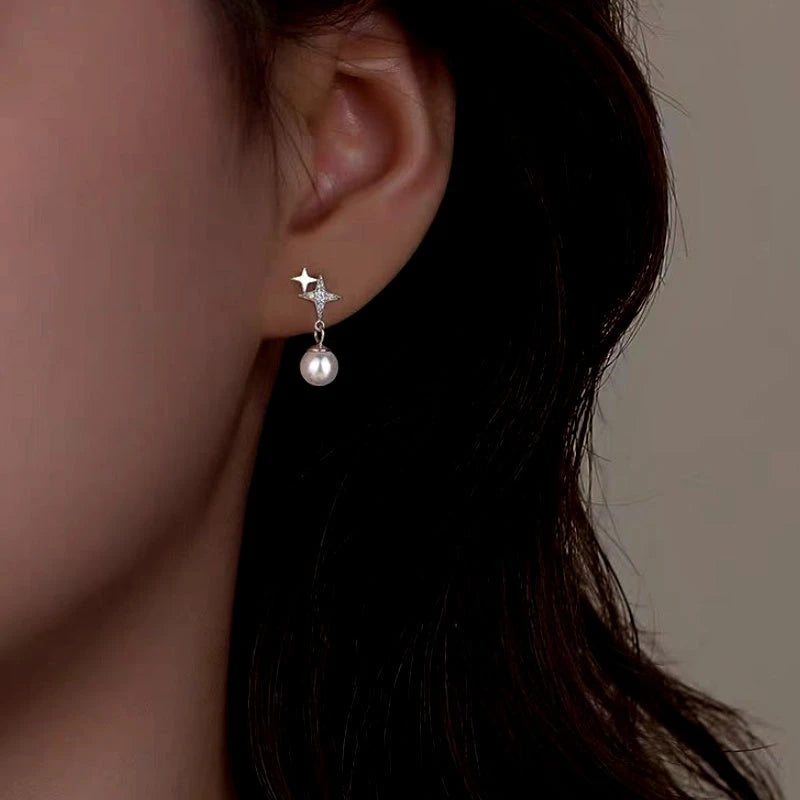 Model showcasing the dangle and style of the Sterling Silver Four-Pointed Star Pearl Earrings