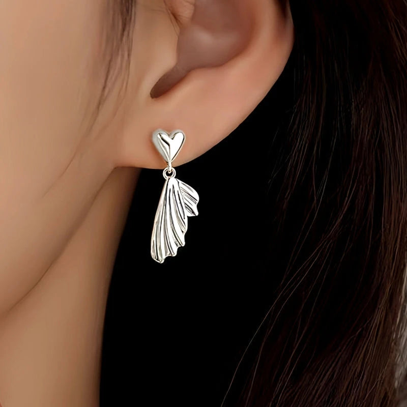 Model showcasing the dangle and style of the Sterling Silver Heart Fishtail Earrings