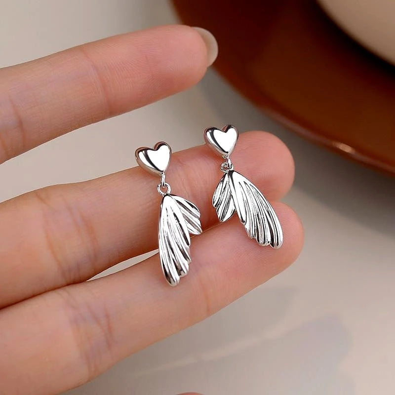 Model showcasing the dangle and style of the Sterling Silver Heart Fishtail Earrings