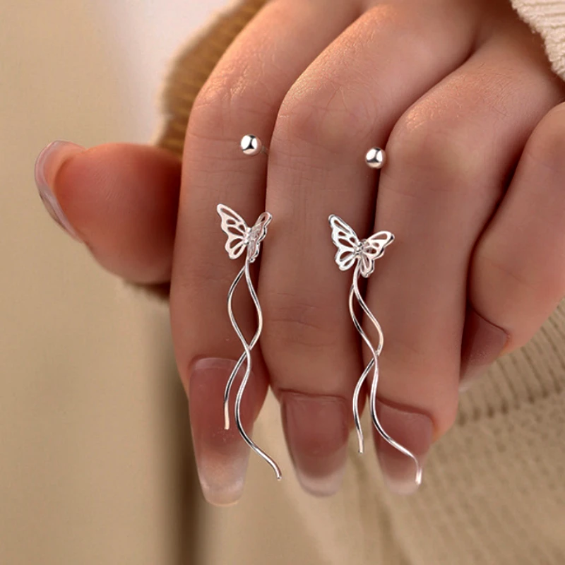 Model showcasing the dangle and style of the Sterling Silver Hollow Butterfy Screw Tassel Earrings