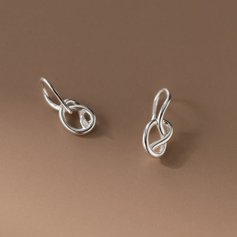 Model showcasing the dangle and style of the Sterling Silver Hollow Heart-Wrapped Ear Hook Earrings