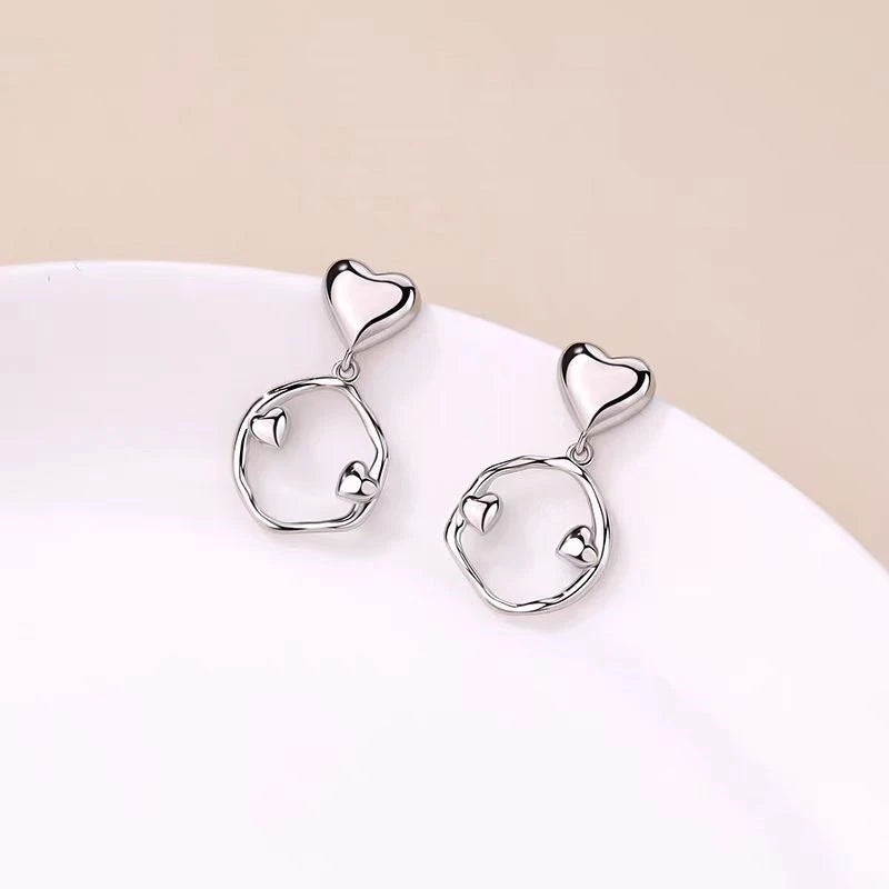 Model showcasing the dangle and style of the Sterling Silver Irregular Hoop Heart Earrings