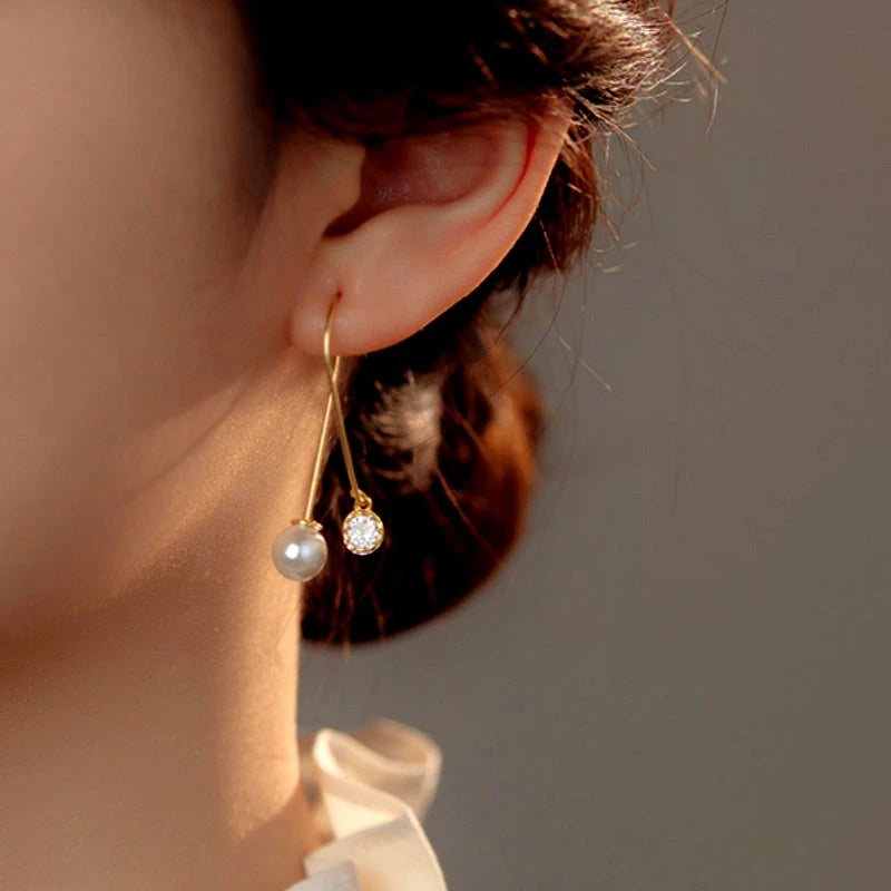 Model showcasing the dangle and style of the Sterling Silver Mermaid Cross Long Pearl Earrings