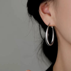 Model showcasing the dangle and style of the Sterling Silver Oval Hoop Earrings