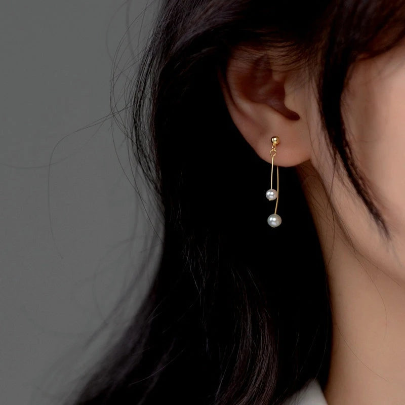 Model showcasing the dangle and style of the Sterling Silver Pearl Cross Earrings