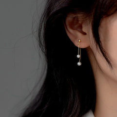 Model showcasing the dangle and style of the Sterling Silver Pearl Cross Earrings