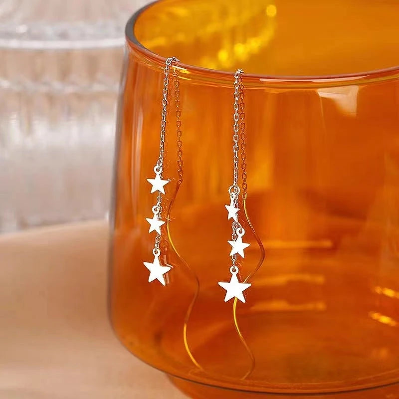 Angled view of the Sterling Silver Wavy Large And Small Star Threader Earrings