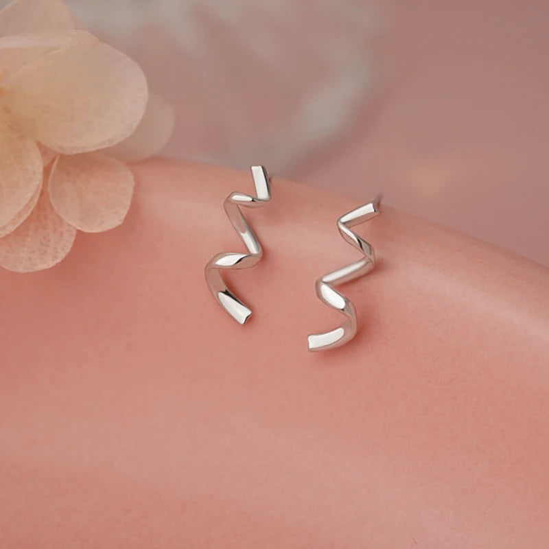 Model showcasing the dangle and style of the Sterling Silver Wavy Ribbon Earrings