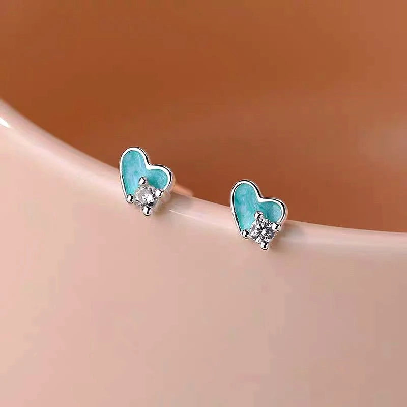 Model showcasing the dangle and style of the Sterling Silver Zircon Blue Heart-Design Stud Earrings