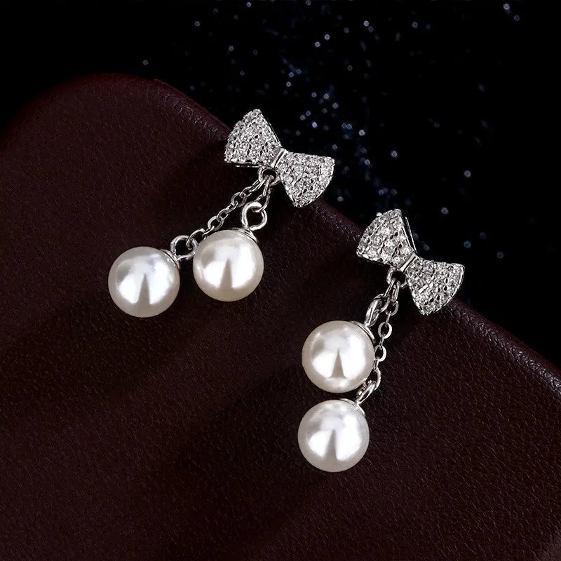 Angled view of the Sterling Silver Zircon Diamond Bow Pearl Tassel Earrings