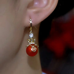 Model showcasing the dangle and style of the 14K Gold-Plated Lucky Money Bag Hypoallergenic Earrings