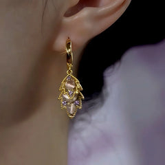 Alternate view of gold leaf huggie hoop drop earring with cat's eye and purple stones on ear