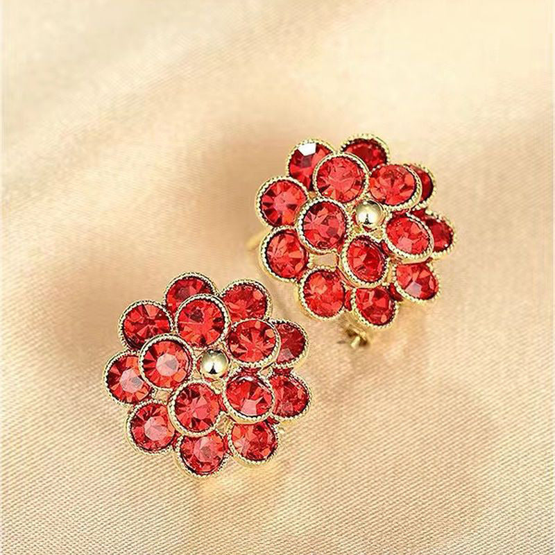 Red crystal flower stud earrings on beige fabric background