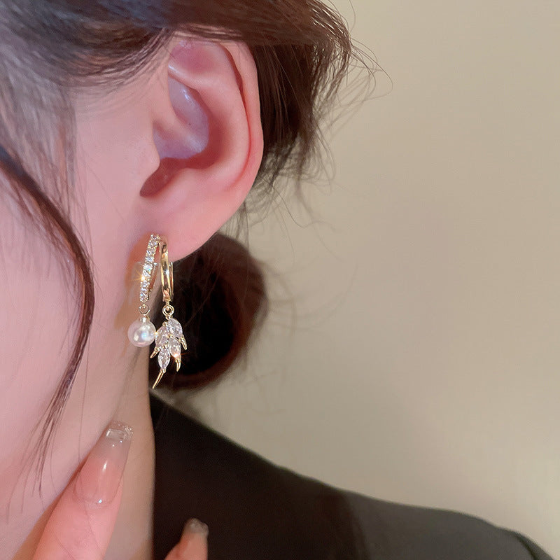 Close-up of gold pearl cubic zirconia leaf double hoop earring on woman's ear
