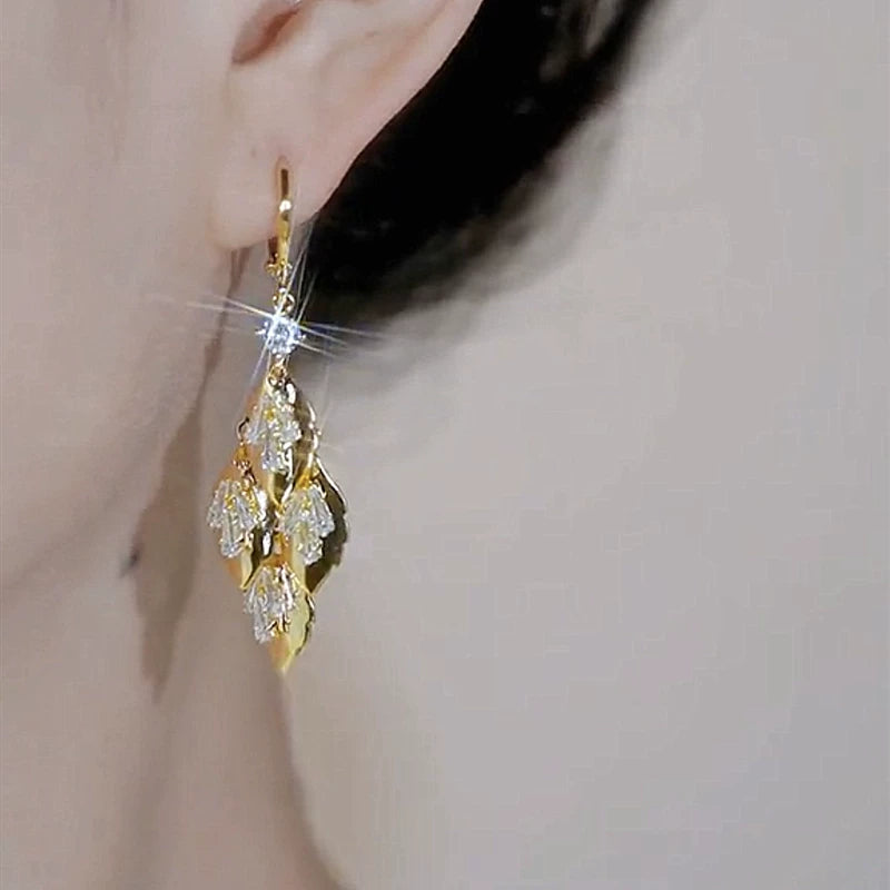 Gold leaf CZ dangle drop earring worn on a woman's ear