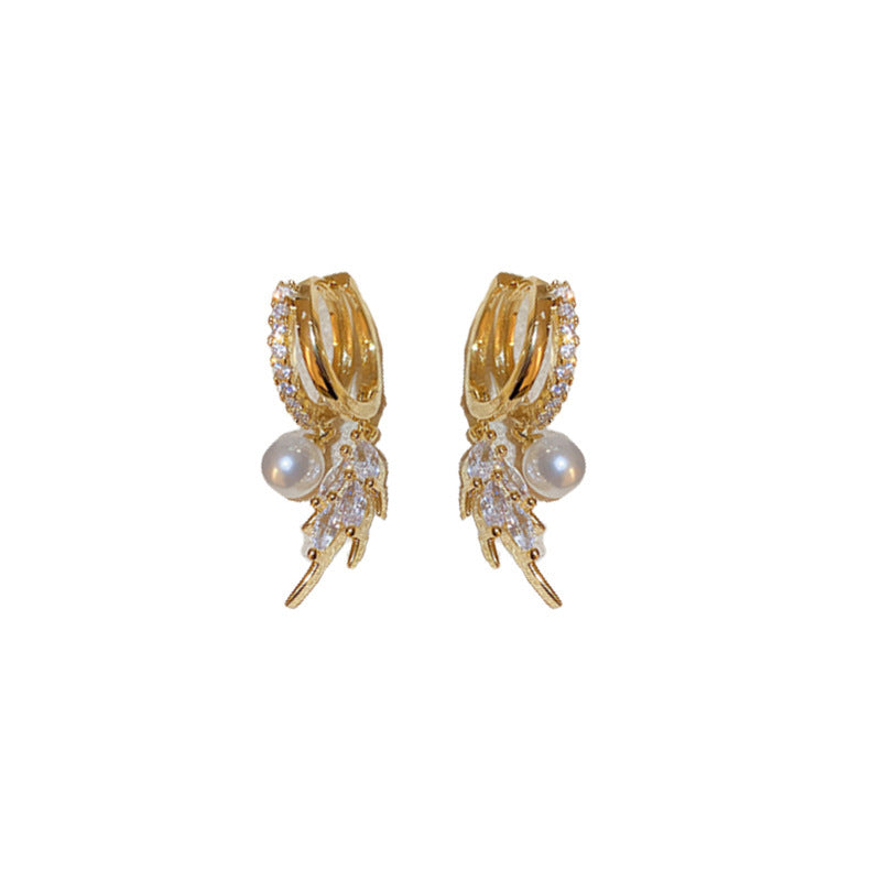 Pair of gold pearl leaf cubic zirconia double hoop earrings on white background
