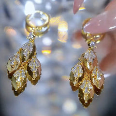 Close up of layered gold leaf drop earrings with baguette CZ accents