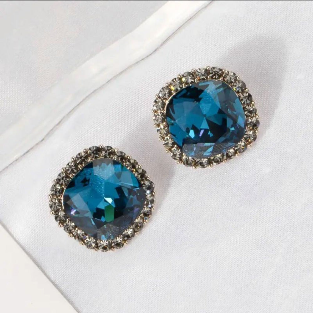 Blue pave border cushion cut crystal stud earrings on white fabric
