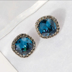 Blue pave border cushion cut crystal stud earrings on white fabric