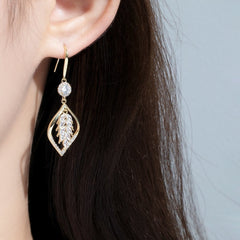 Gold cubic zirconia leaf drop earring worn on woman's ear with dark hair